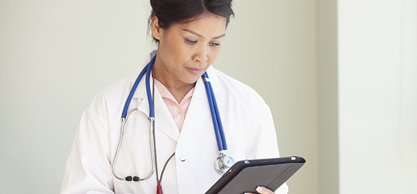 Une femme munie d’un stéthoscope scrute sa tablette