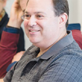 Man in collared shirt smiling.