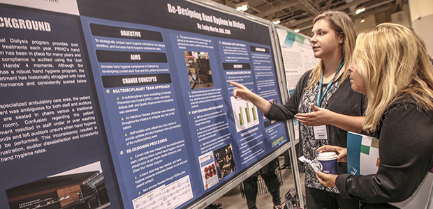 Two women looking at an academic poster at the Health Quality Transformation 2015 conference.