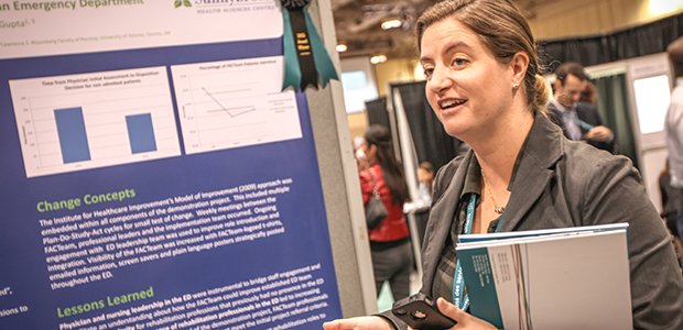 Une femme en train de parler devant l'affiche d'une université à la conférence Transformation Qualité de la santé 2015.