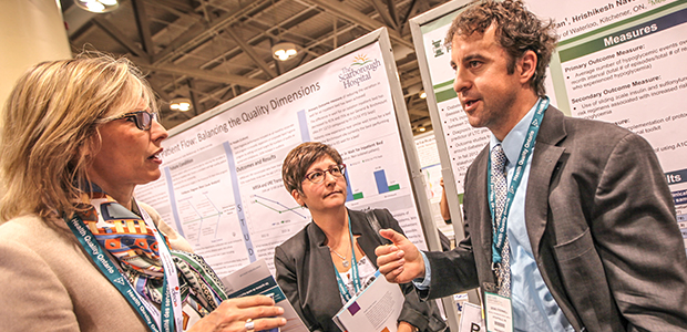 Two women and one man talking in front of an academic poster at the Health Quality Transformation 2015 conference. 