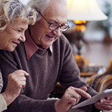 A senior couple looking at their tablet together