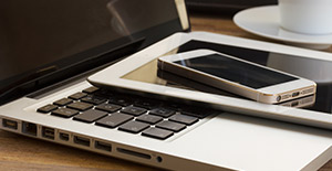 A laptop, iPad and cell phone stacked on top of each other