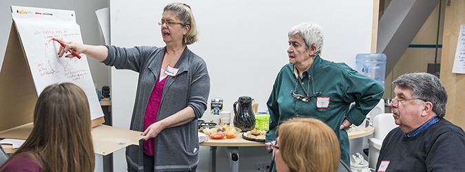 Person stands at front of room teaching a group on a flip chart