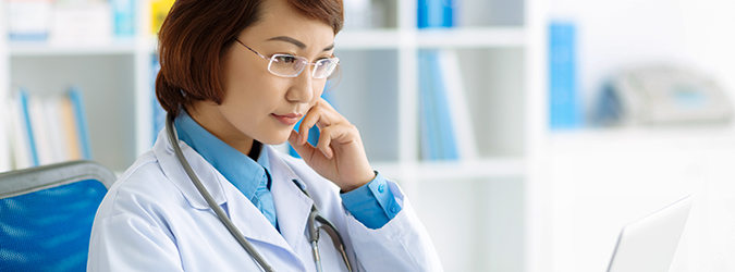 Female clinician reviews computer in office