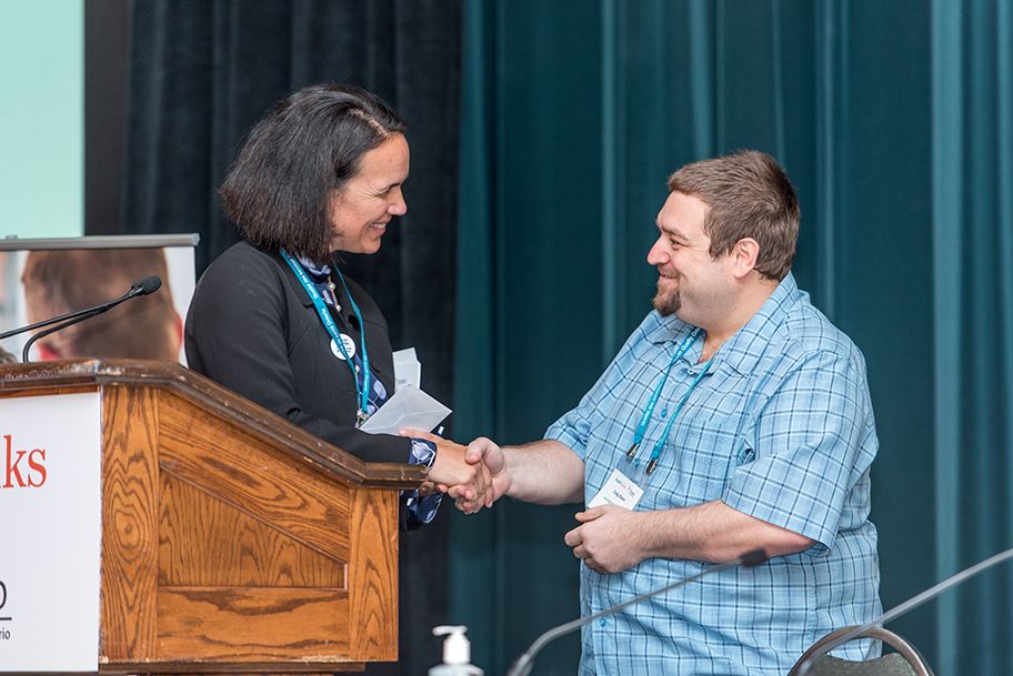 Lee Fairclough shaking hands with a patient speaker onstage