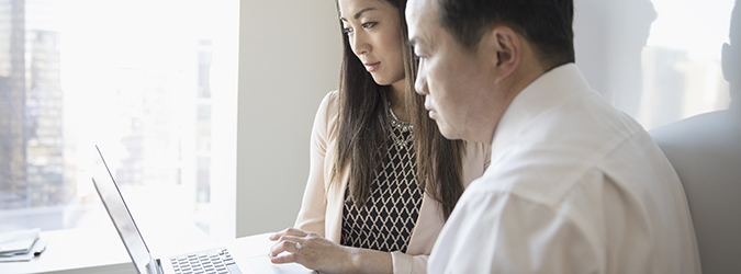 Une femme et un homme qui consultent des documents à l’ordinateur