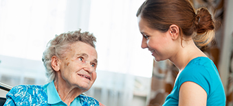 A health care provider caring for a senior patient in a wheelchair