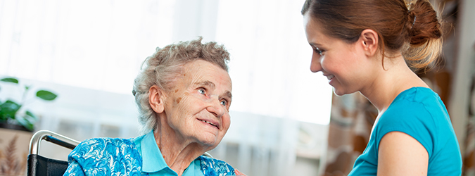 A health care provider caring for a senior patient in a wheelchair