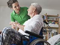 Une patiente en fauteuil roulant reçoit de l'aide de son professionnel de la santé