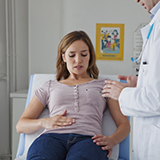 A doctor caring for a female patient who is telling him about pain in her stomach