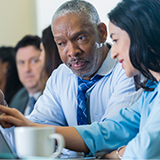 Man and woman discussing a quality improvement report on a computer screen