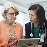 Two health care professionals searching for system performance information on a computer in a hospital office