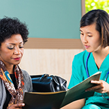 Female nurse tending to female patient in waiting room